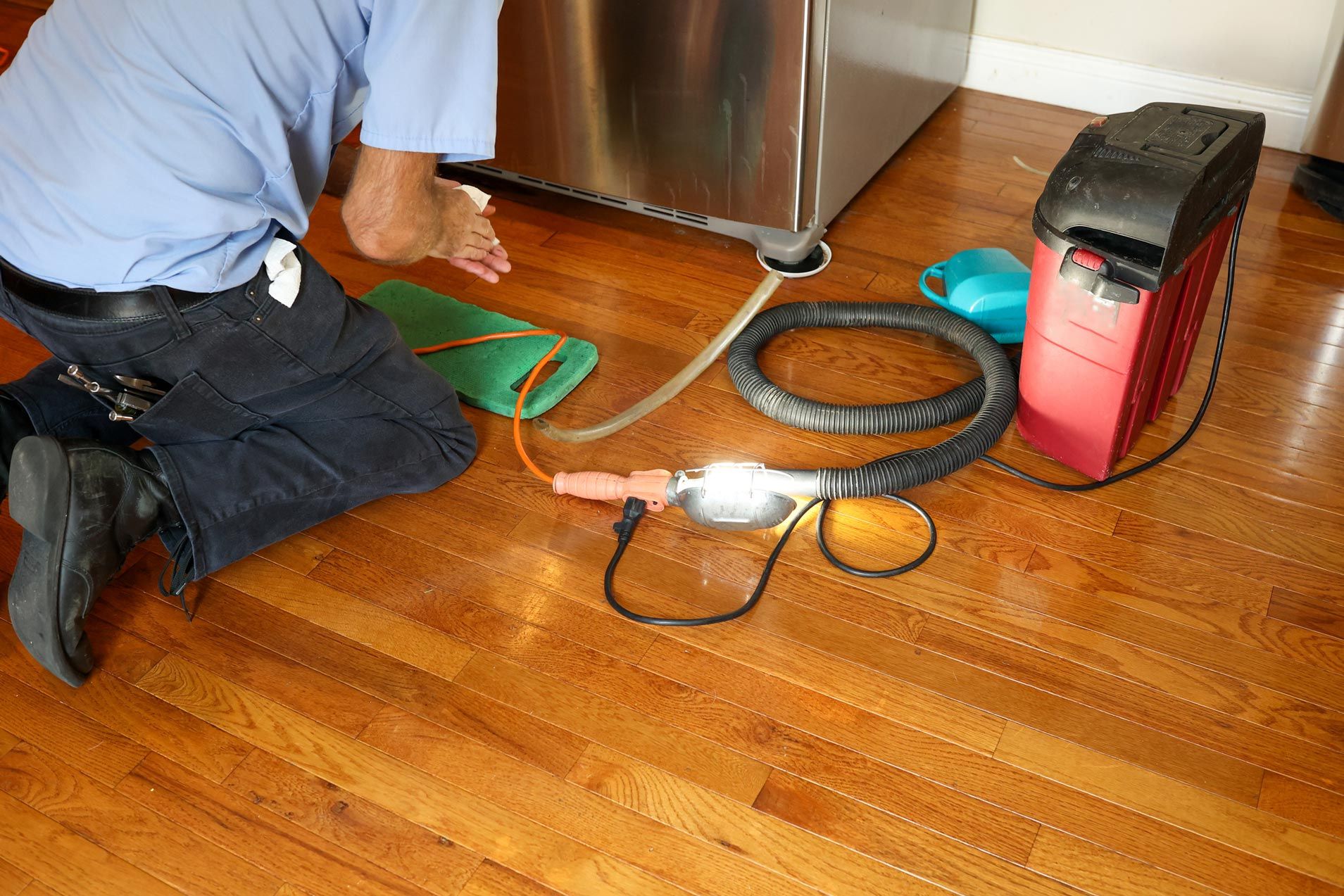 A man repairing a leaking refrigerator