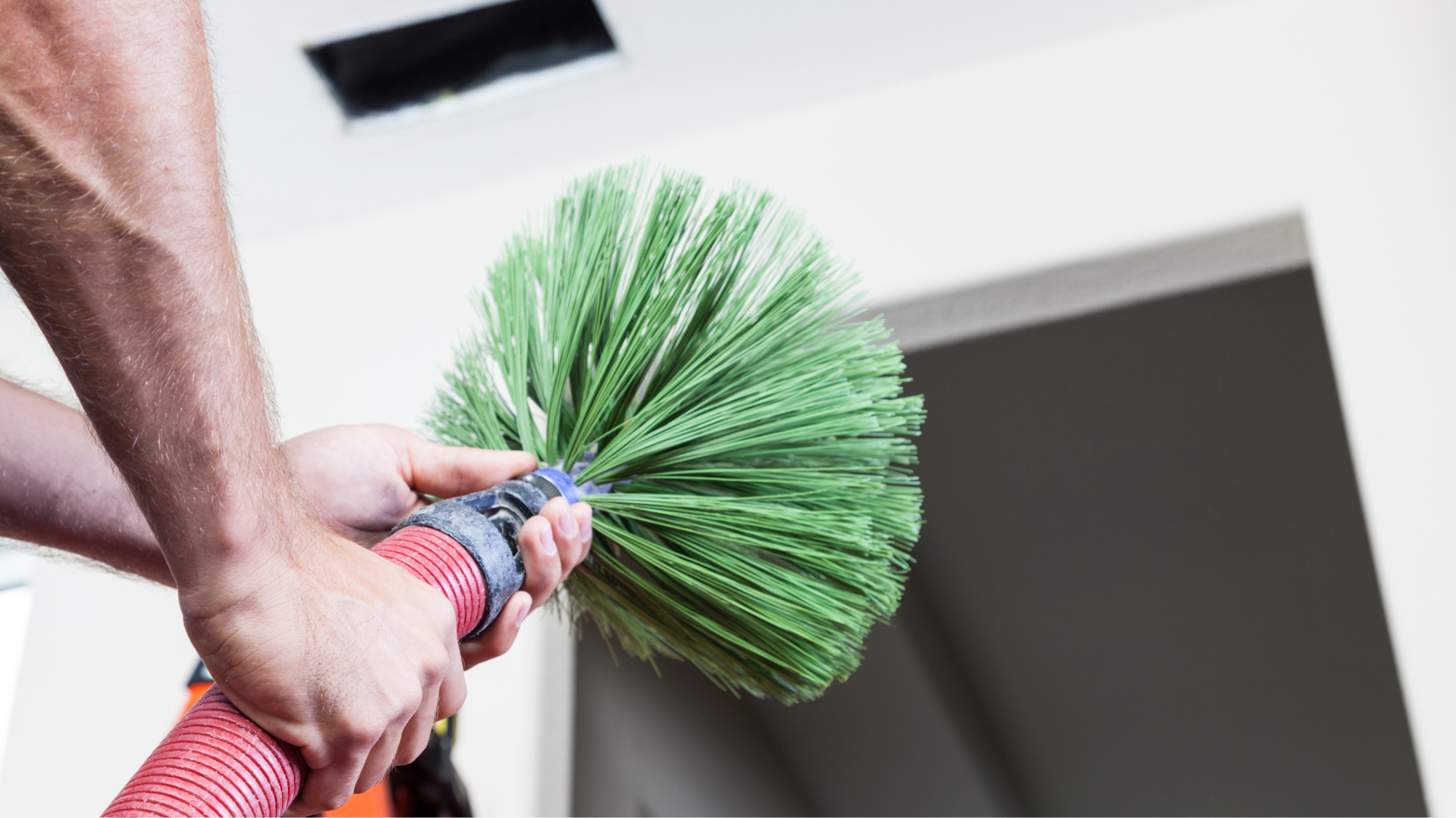 A person is holding a green broom in their hands.