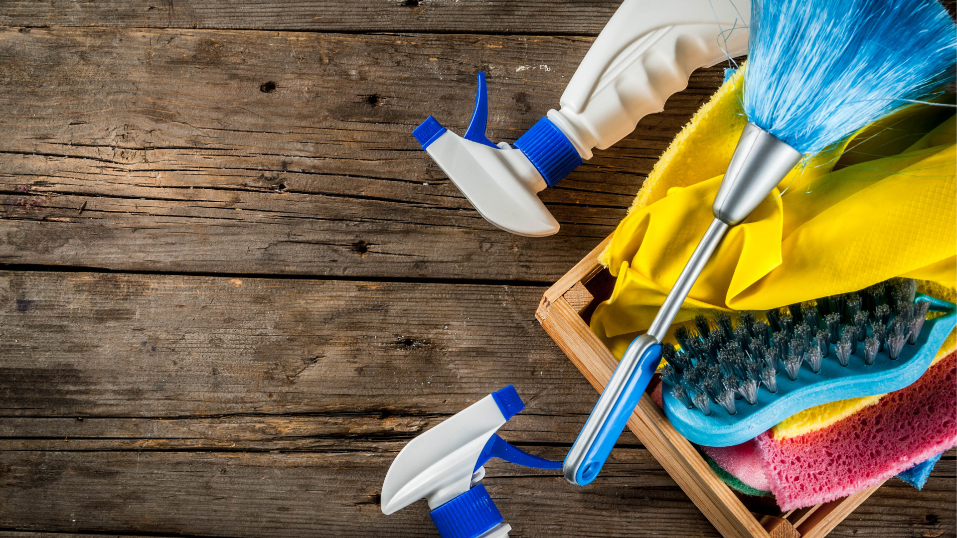 A wooden box filled with cleaning supplies on a wooden table.
