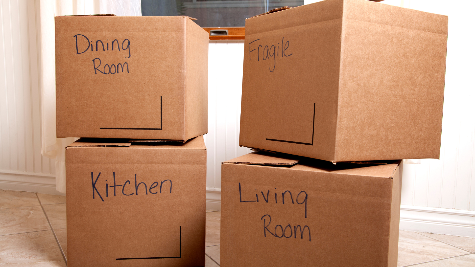 Four cardboard boxes are stacked on top of each other labeled kitchen living room and dining room