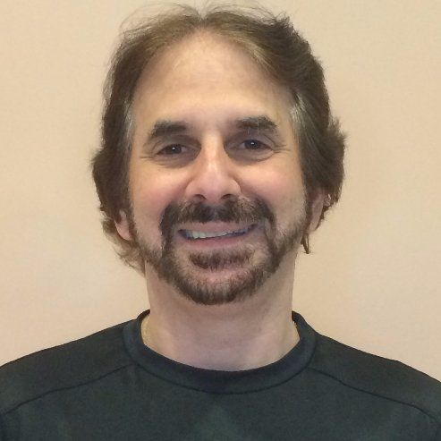 A man with a beard is smiling and wearing a black shirt