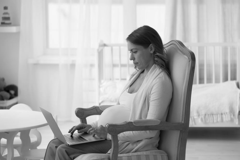 pregnant woman looking at her laptop, doing research about std/sti tests when pregnant