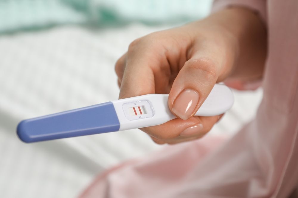 A woman holding a positive pregnancy test.