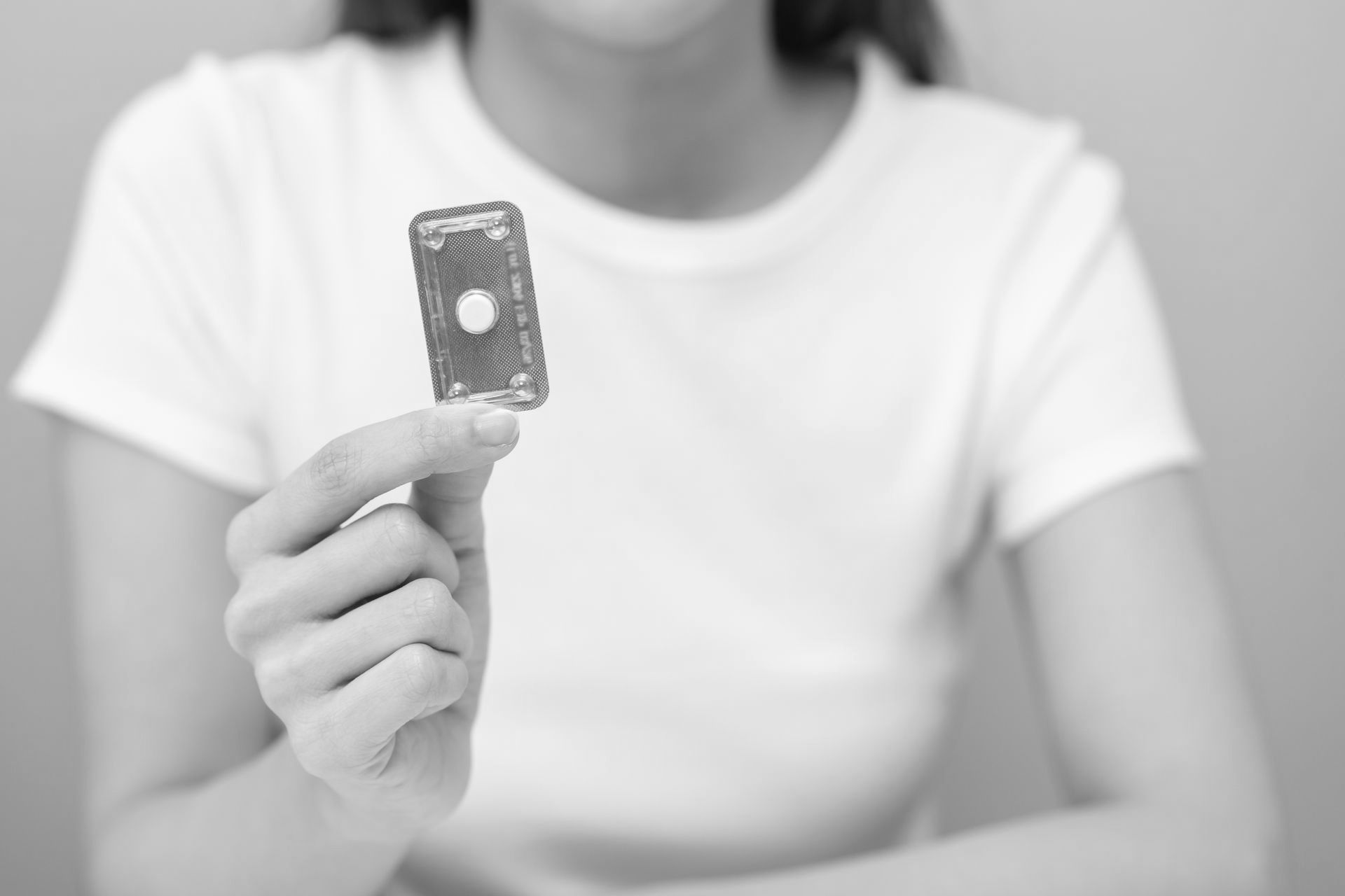 A woman is holding a pill in her hand.