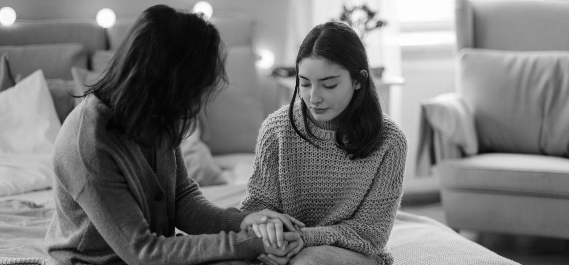 A mom counsels her daughter and holds her hand.