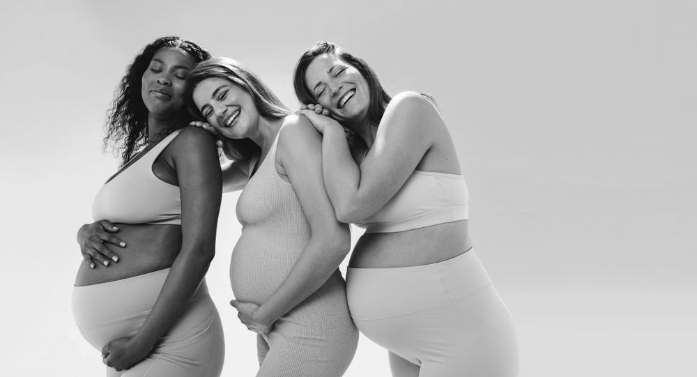 Three pregnant women are posing for a picture together.