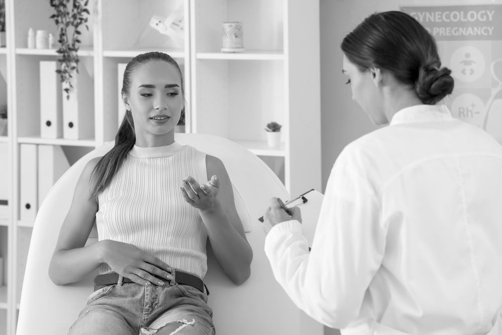 A woman is sitting in a chair talking to a doctor.