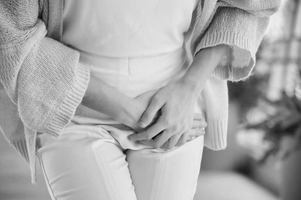 A woman is holding her stomach with her hands.