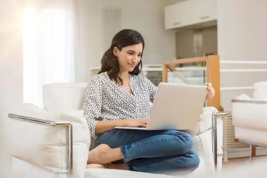 A woman is sitting in a chair using a laptop computer.