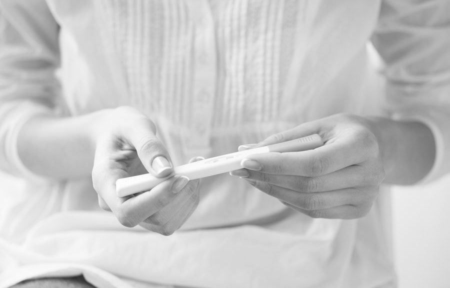 A woman is holding a pregnancy test in her hands.