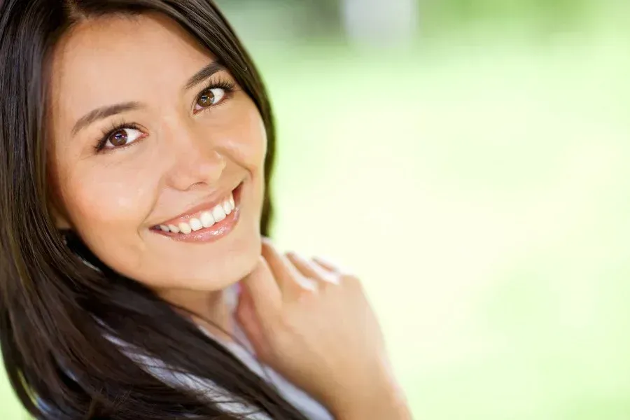 A woman with long black hair is smiling for the camera.