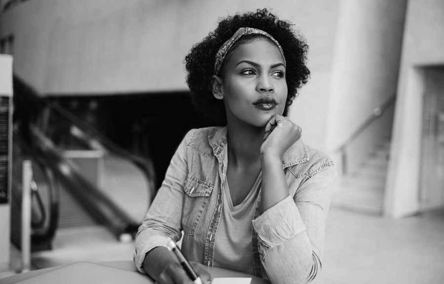 A woman is sitting at a table with a pen in her hand.