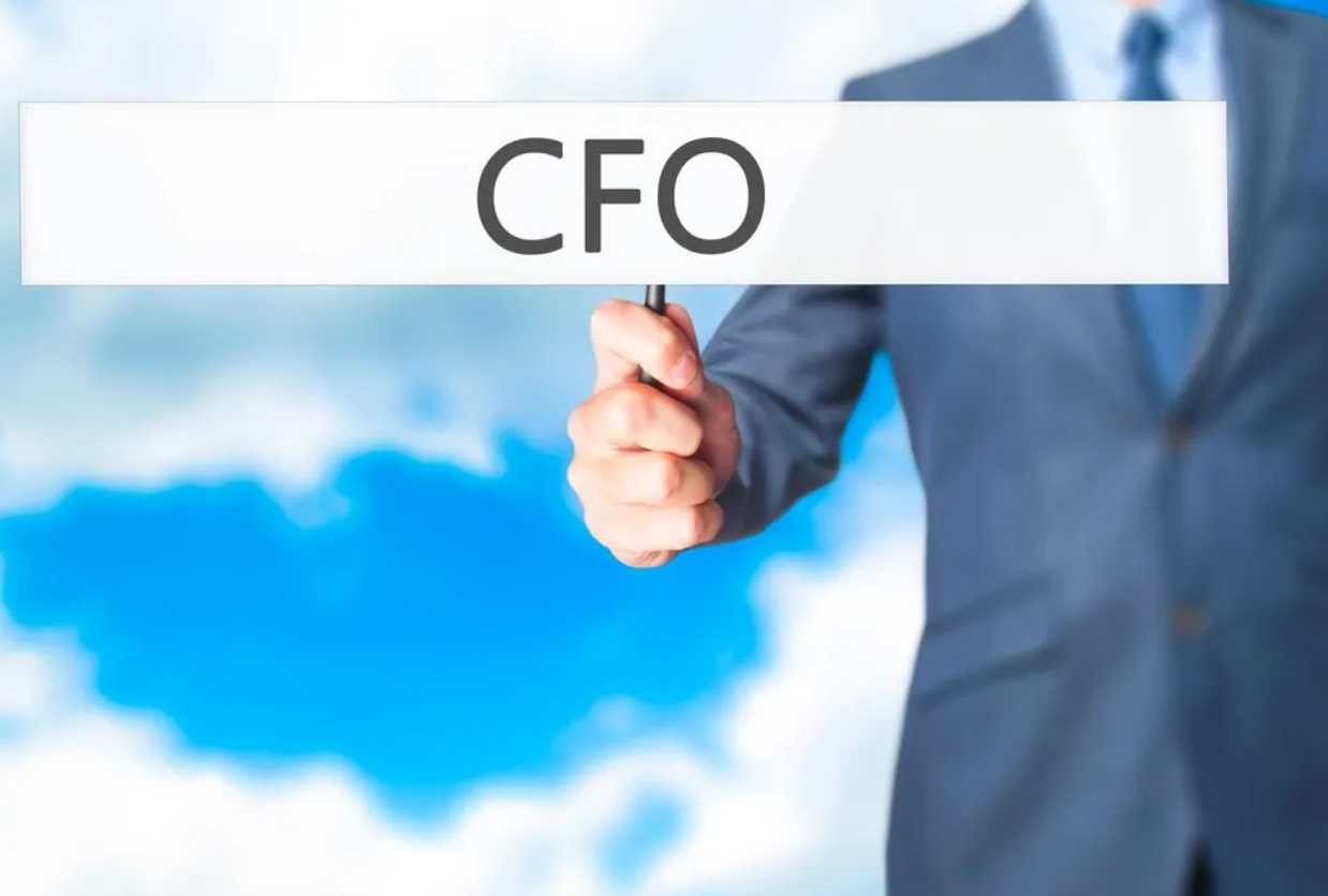 A person in a business suit holding up a white sign with the text 