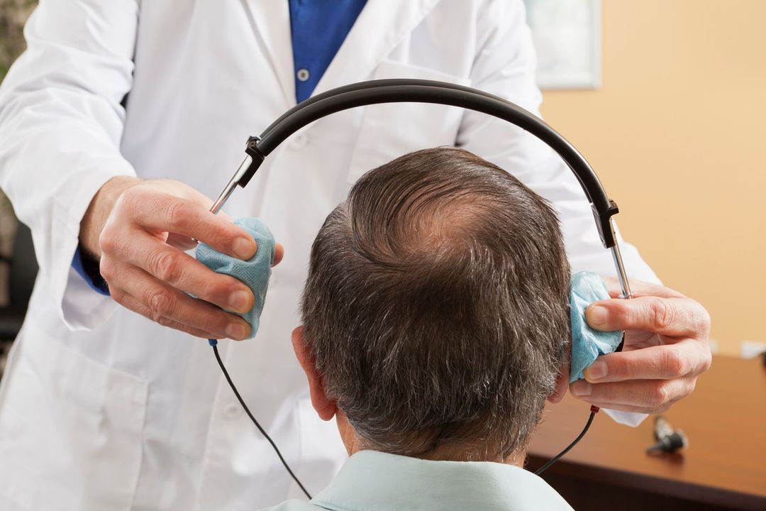 Un medico esamina l'udito di un uomo con le cuffie.