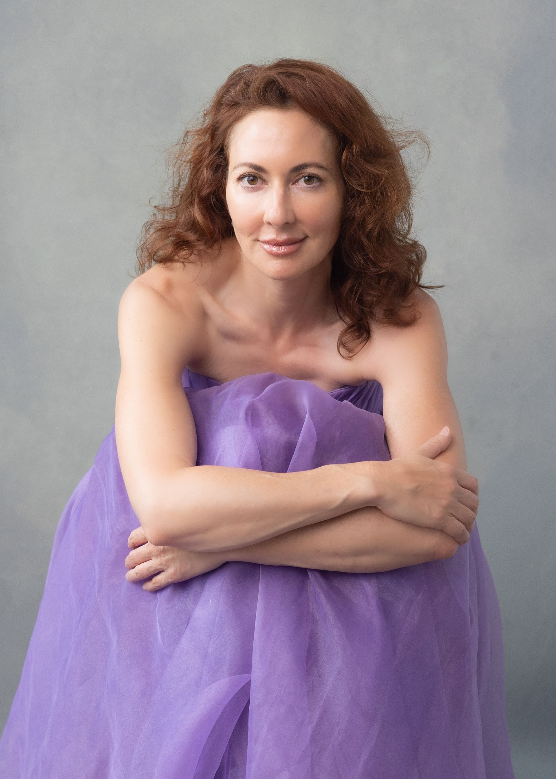 A woman in a green dress is sitting on a chair.