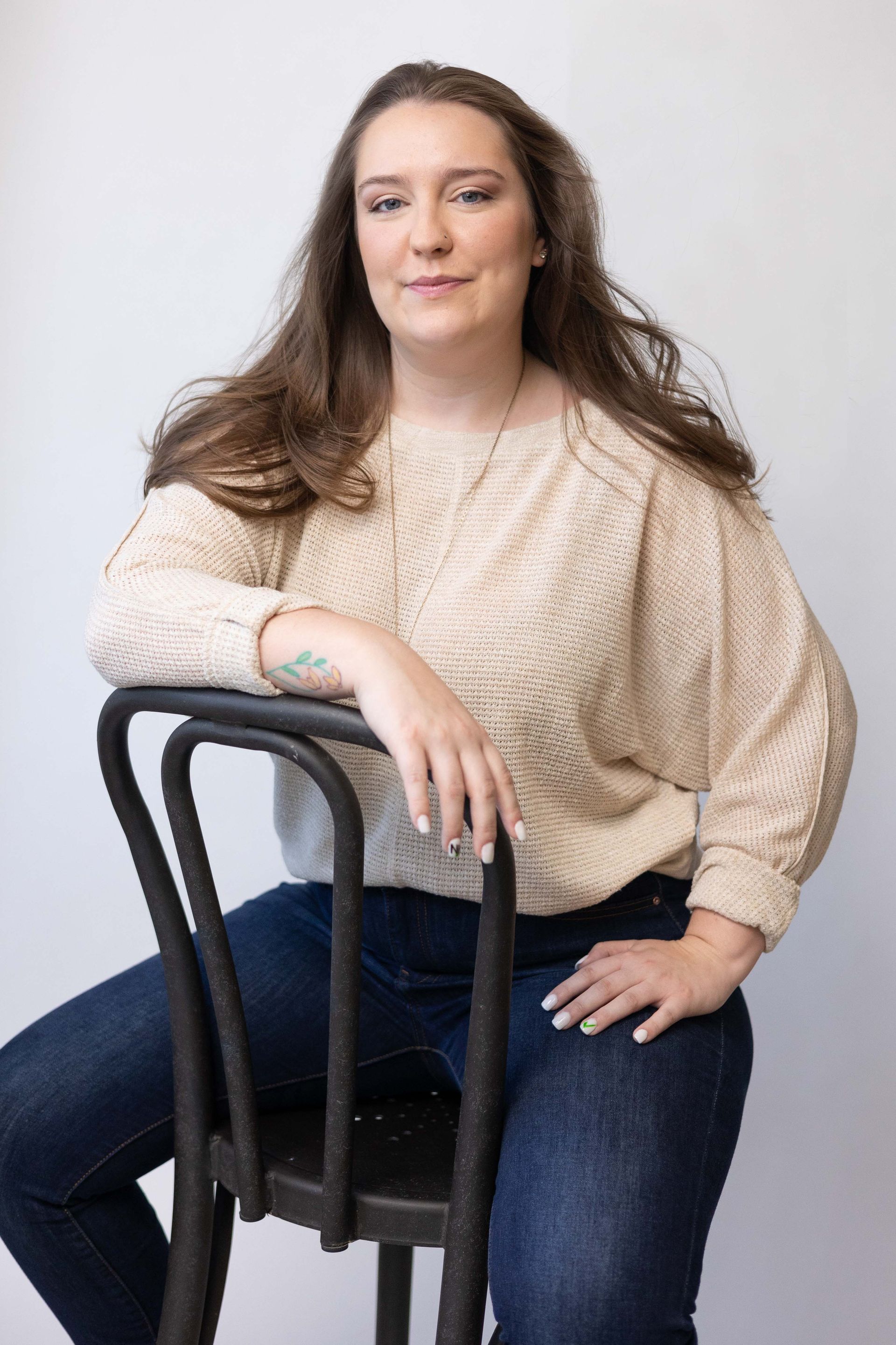 A woman in a sweater and jeans is sitting on a chair.