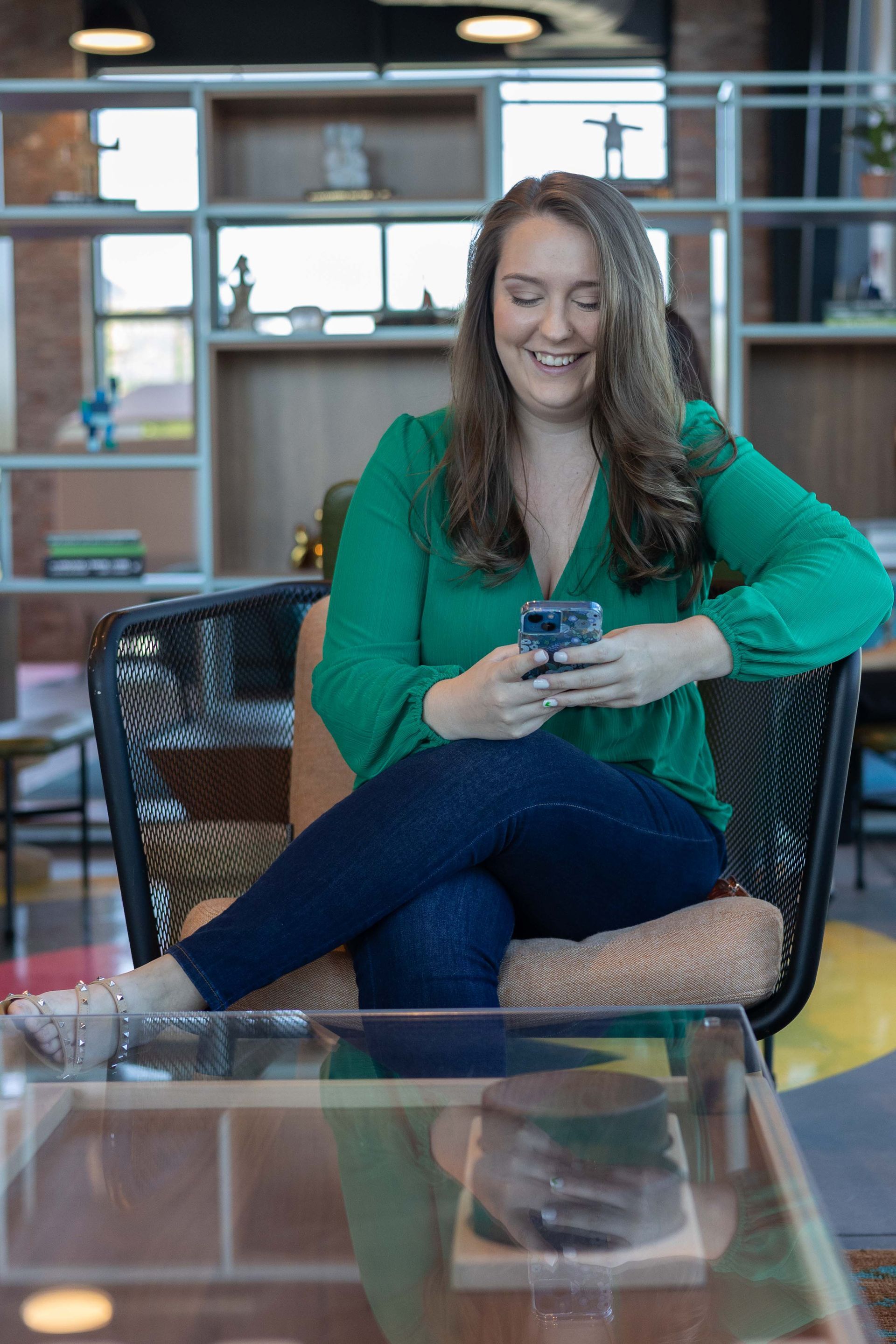 A woman is sitting in a chair looking at her cell phone.