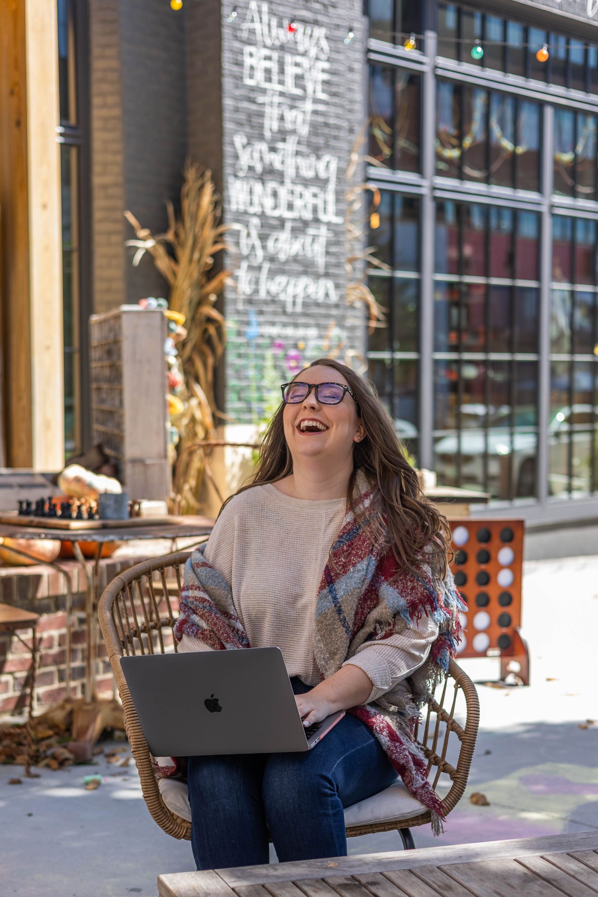 A woman is sitting in a chair with a laptop on her lap.