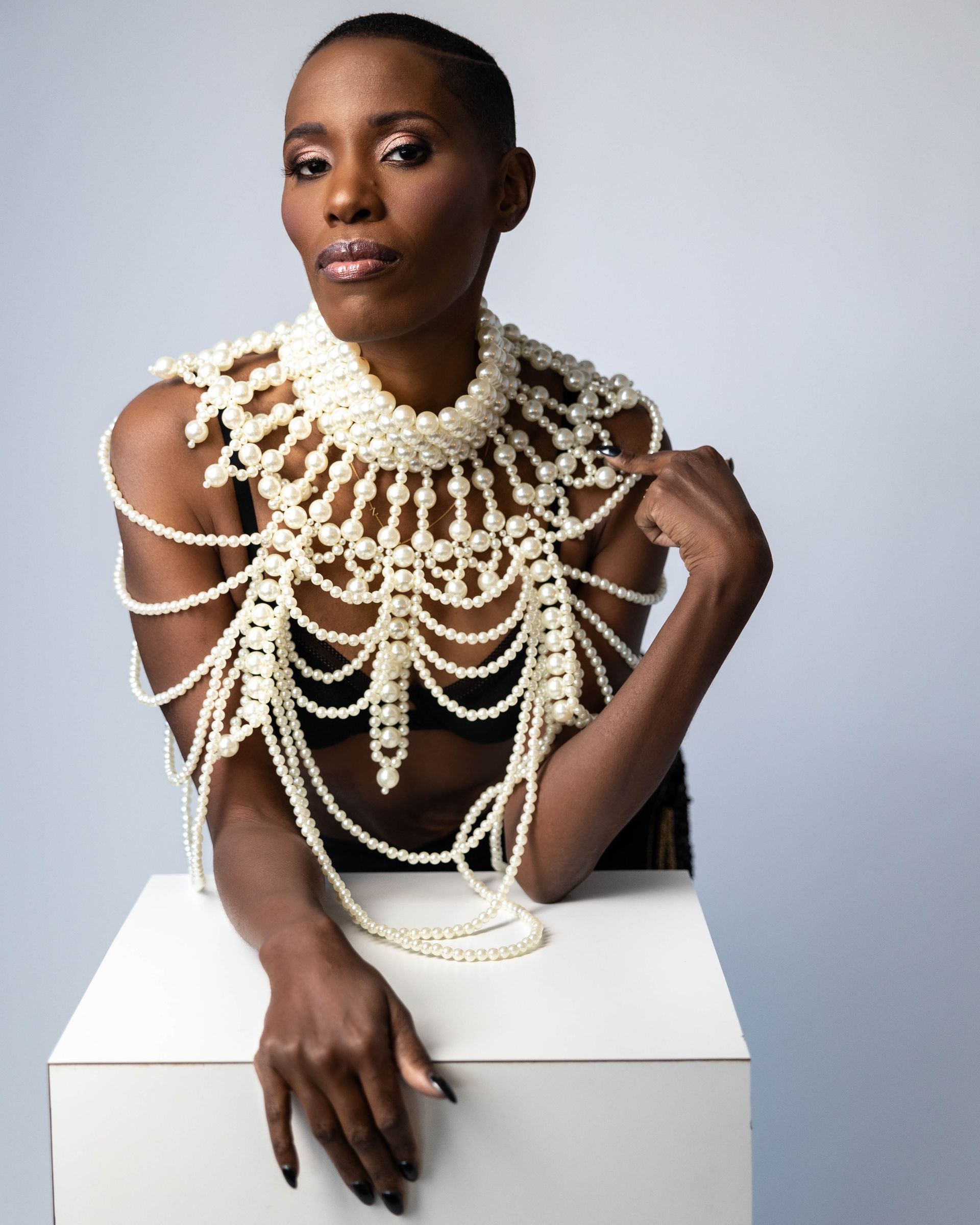 A woman in a long ruffled dress is sitting on a chair.