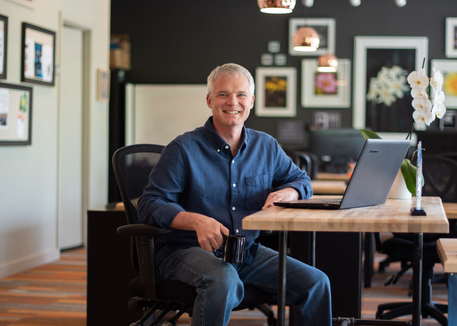 A man is sitting at a desk with a laptop on it.