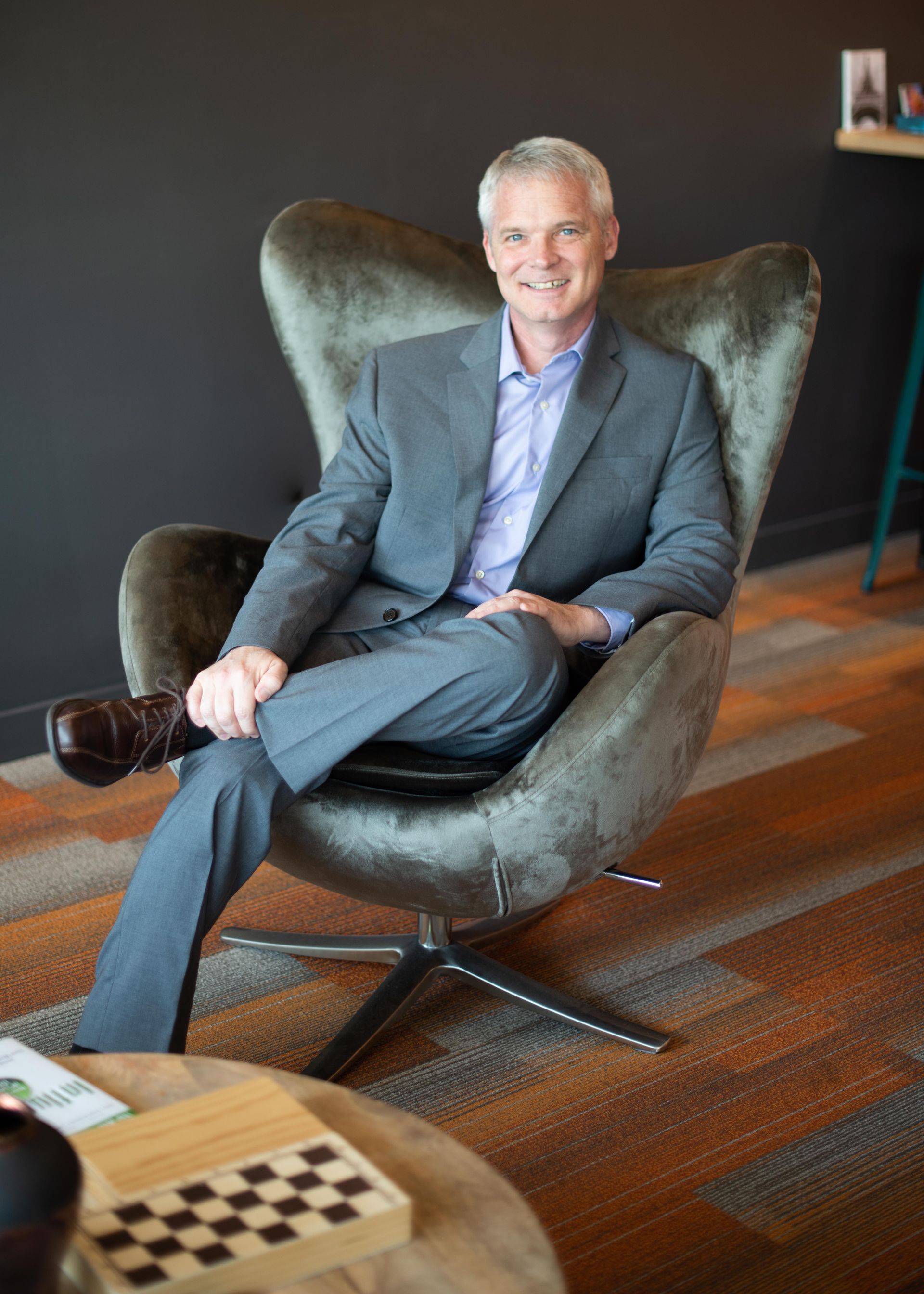 A man in a suit is sitting in a chair with his legs crossed.
