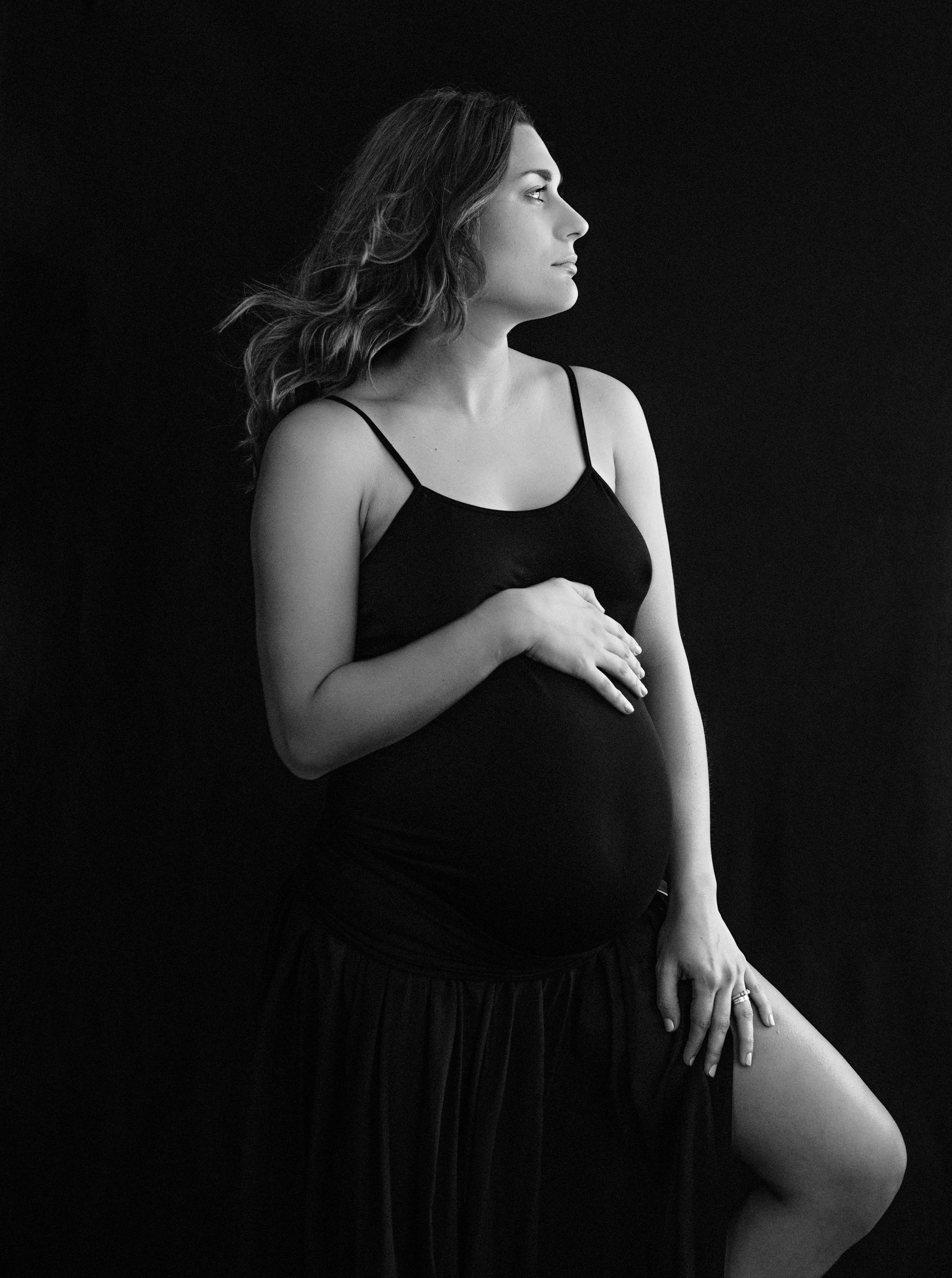A black and white photo of a pregnant woman in a black dress