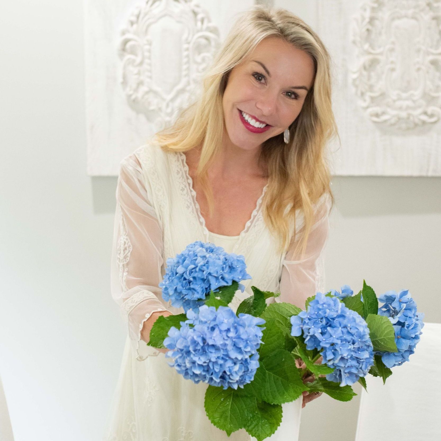 A woman in a white dress is holding a bouquet of blue flowers.