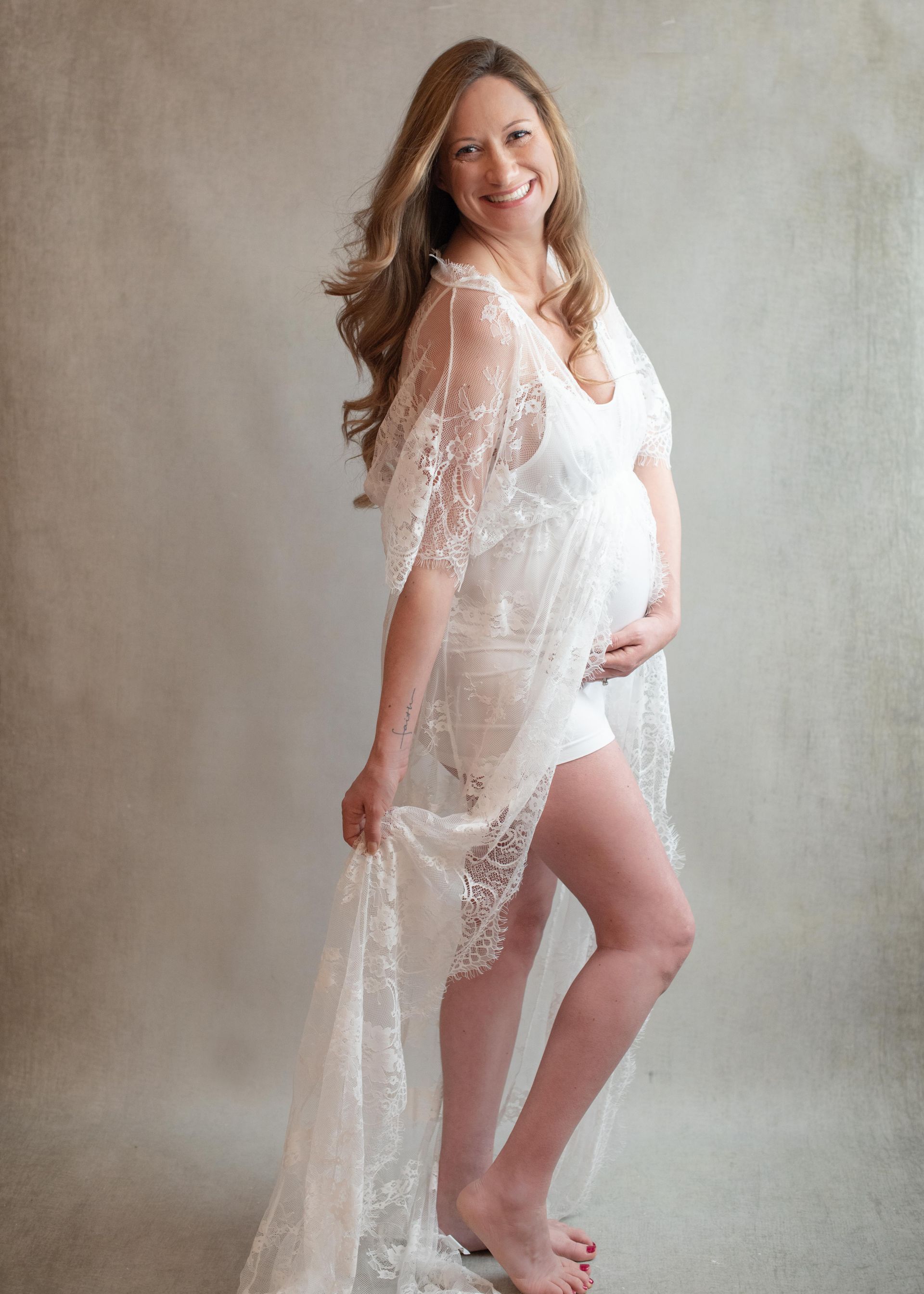 A woman in a black lace dress is holding a baby.