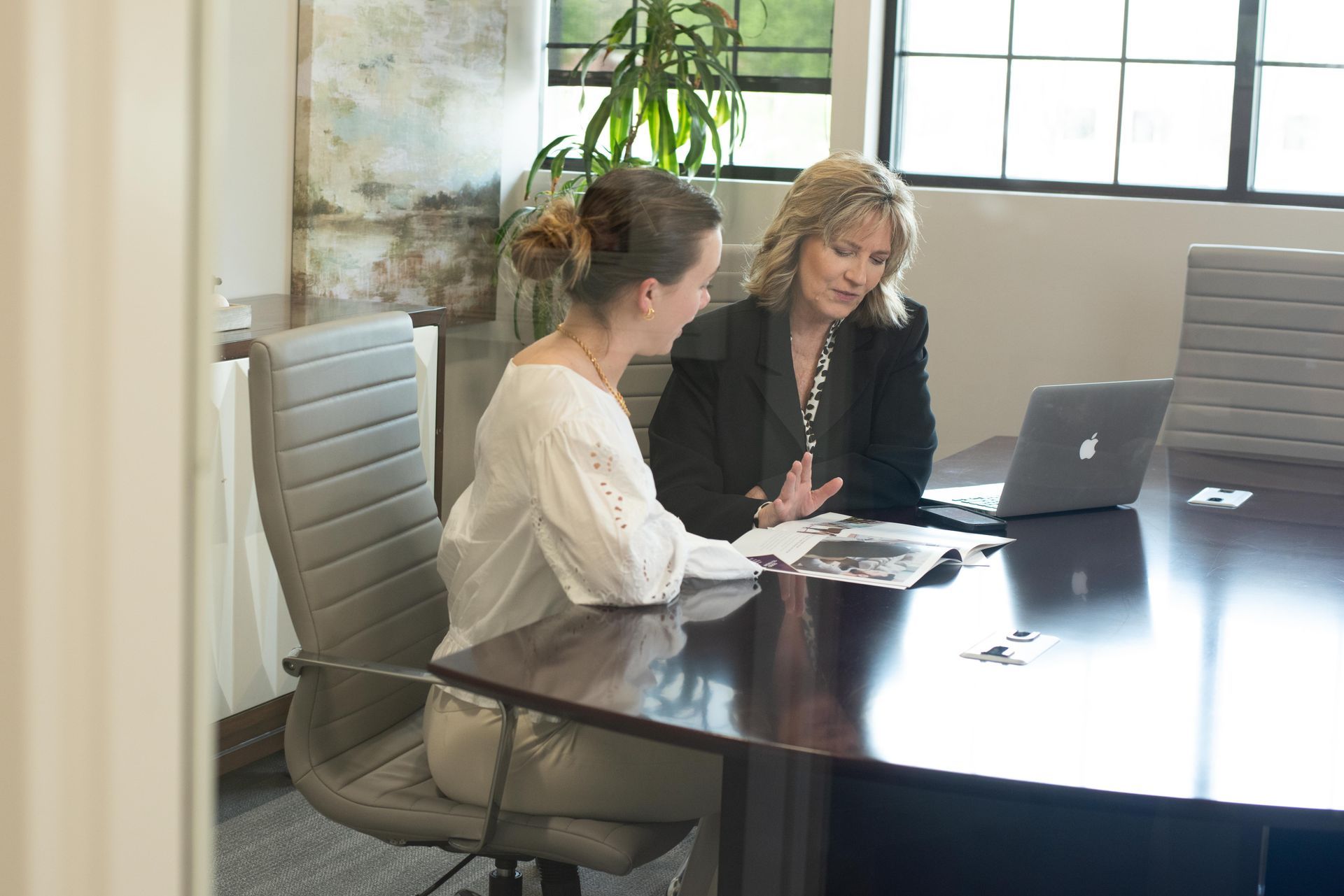 Two women are sitting at a table with a laptop.