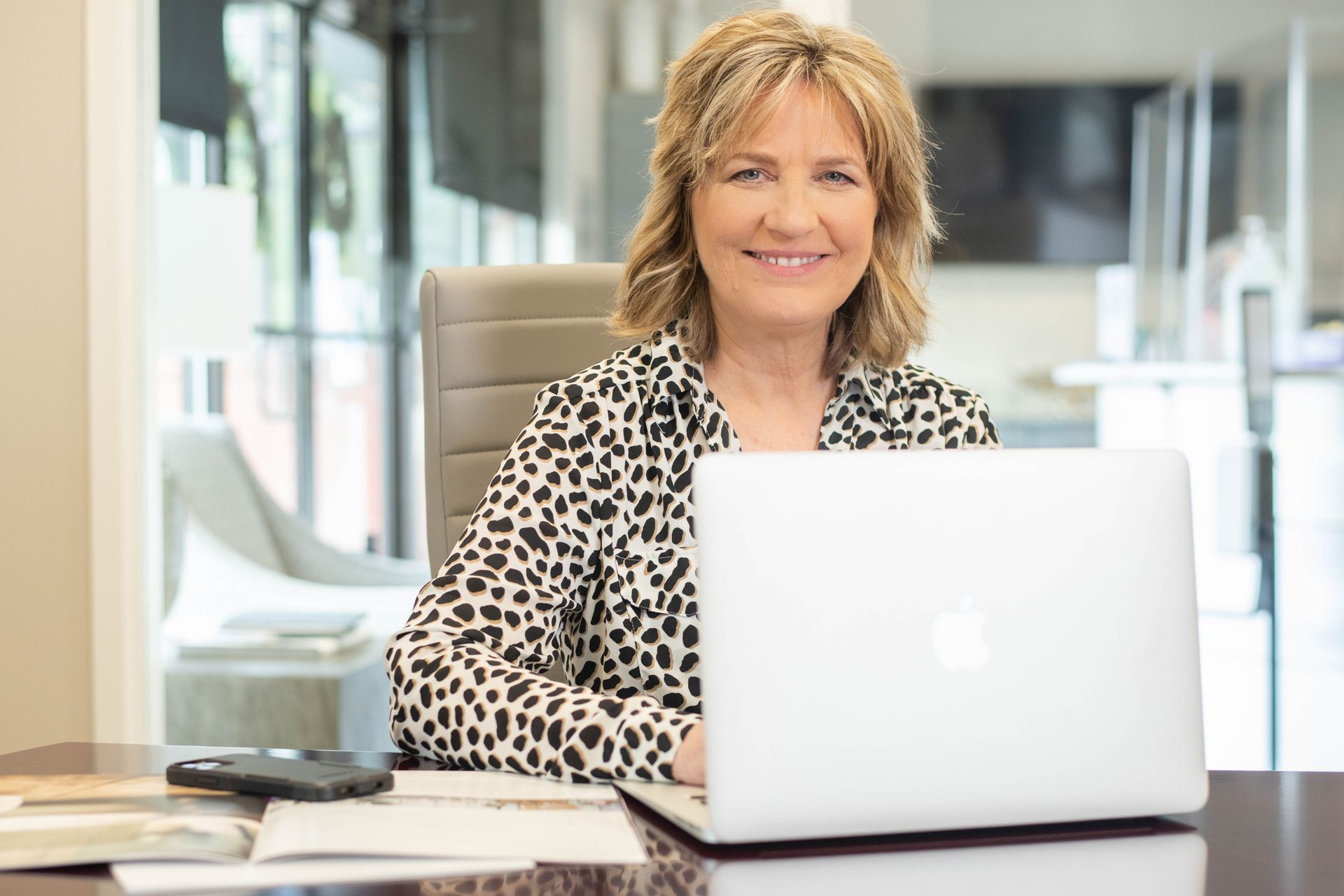 A woman is sitting at a desk with a laptop computer.
