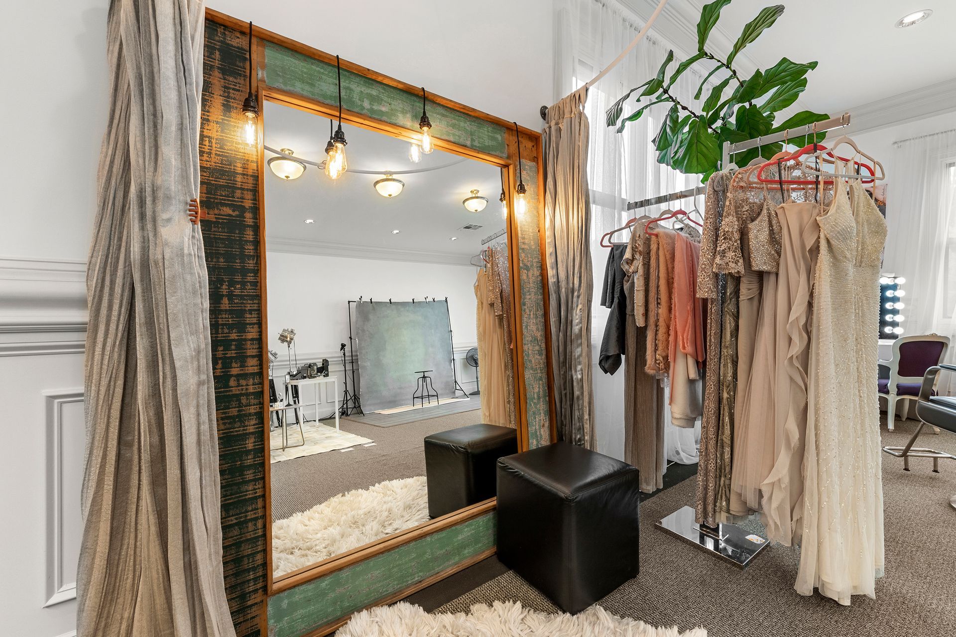 A room with a large mirror and clothes hanging on racks.