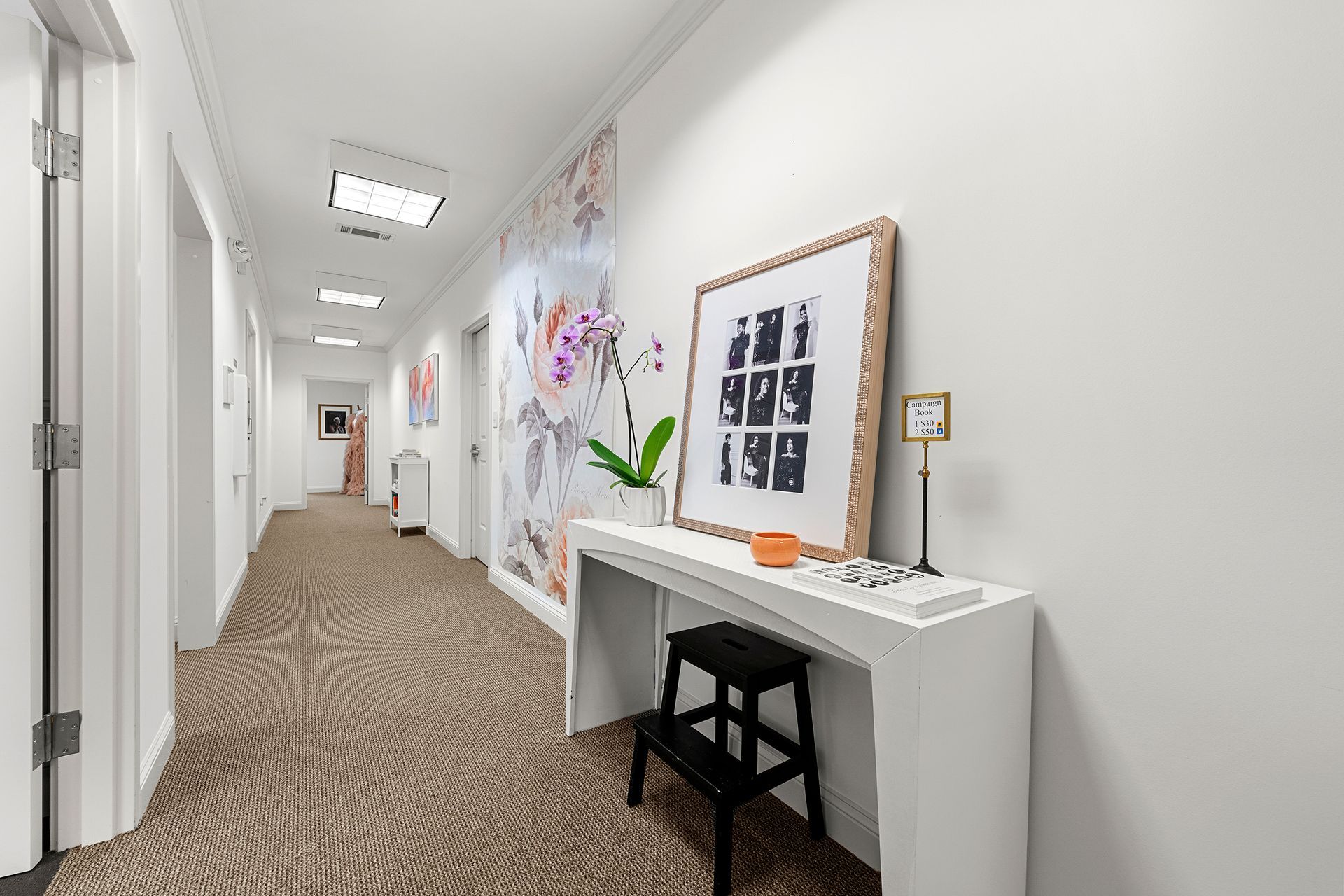 A long hallway with a table and a picture on the wall.