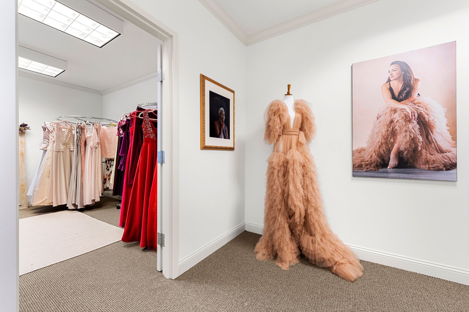 A room with a mannequin in a dress and a picture on the wall.