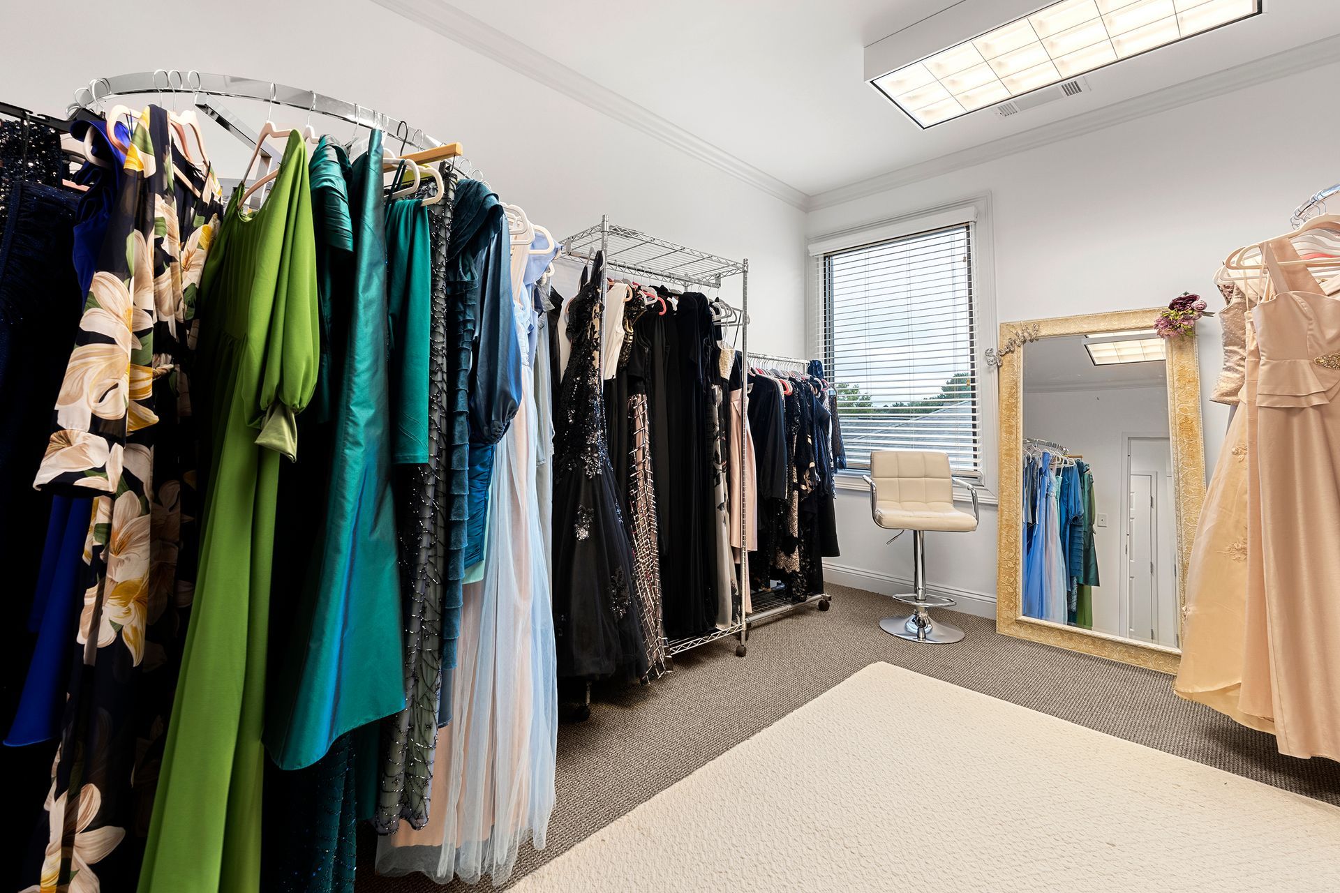 A room filled with lots of dresses and a mirror.