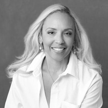 A black and white photo of a woman wearing a white shirt and smiling.