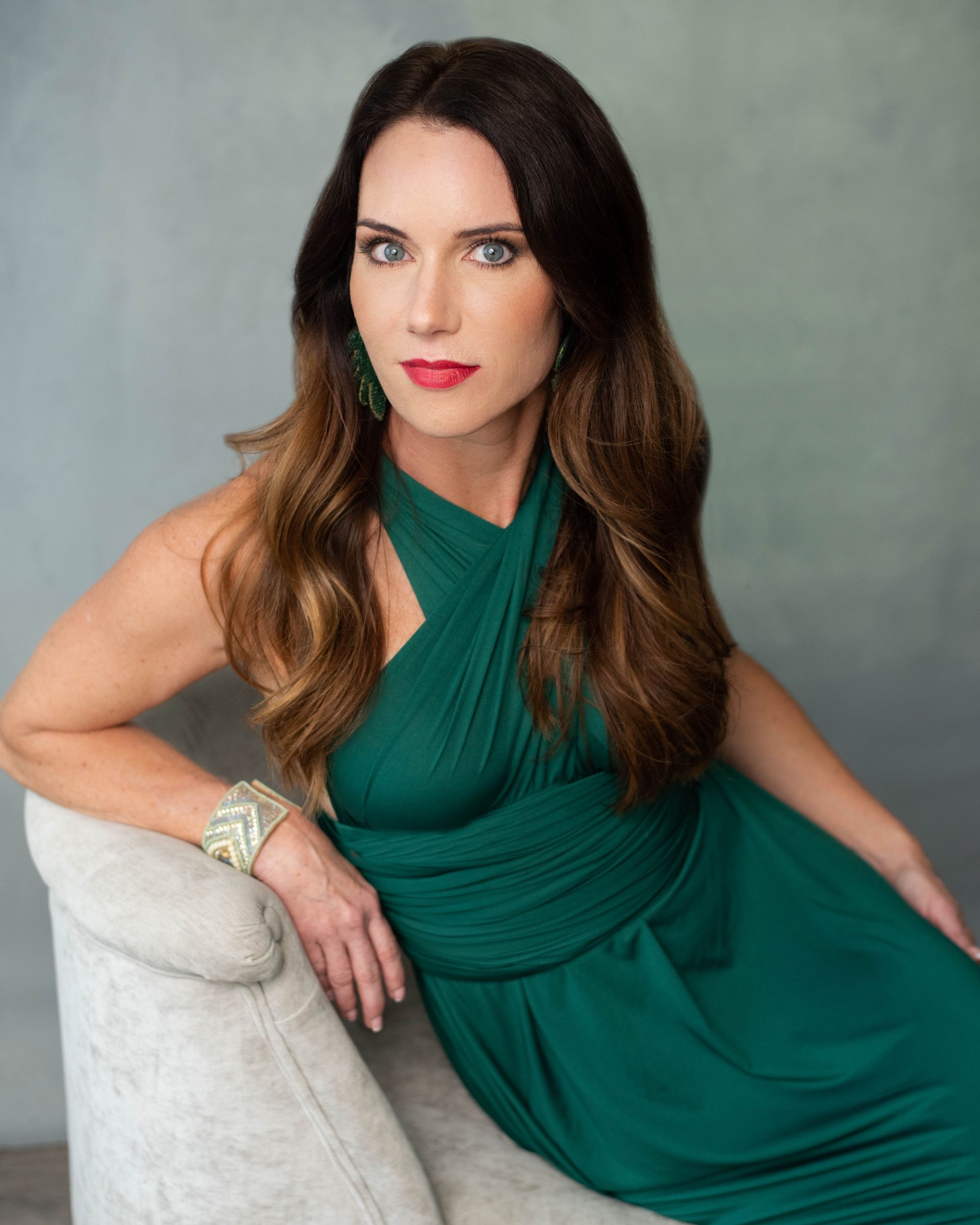 A woman in a green dress is sitting on a chair.