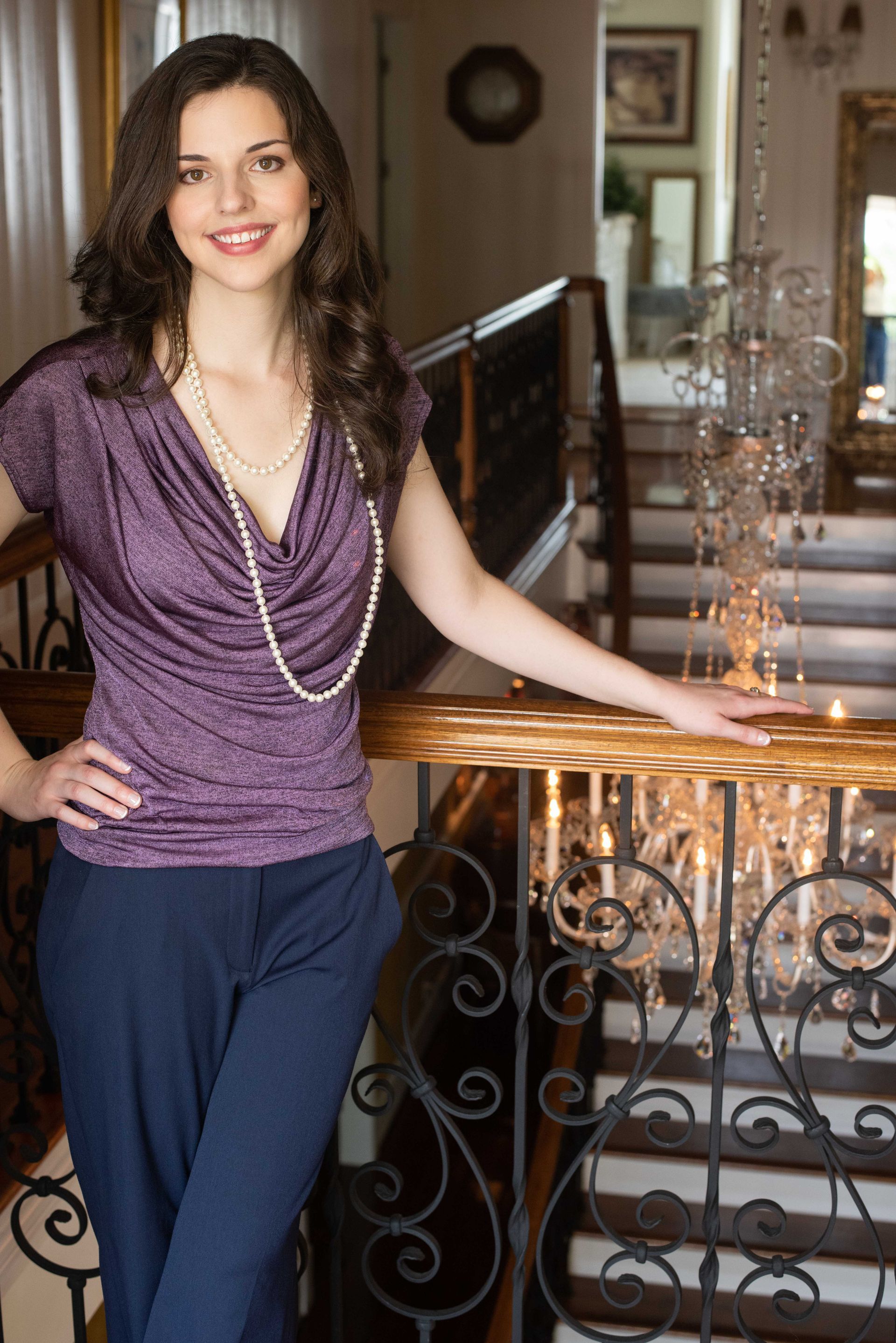A woman in a purple top and blue pants is standing on a railing.
