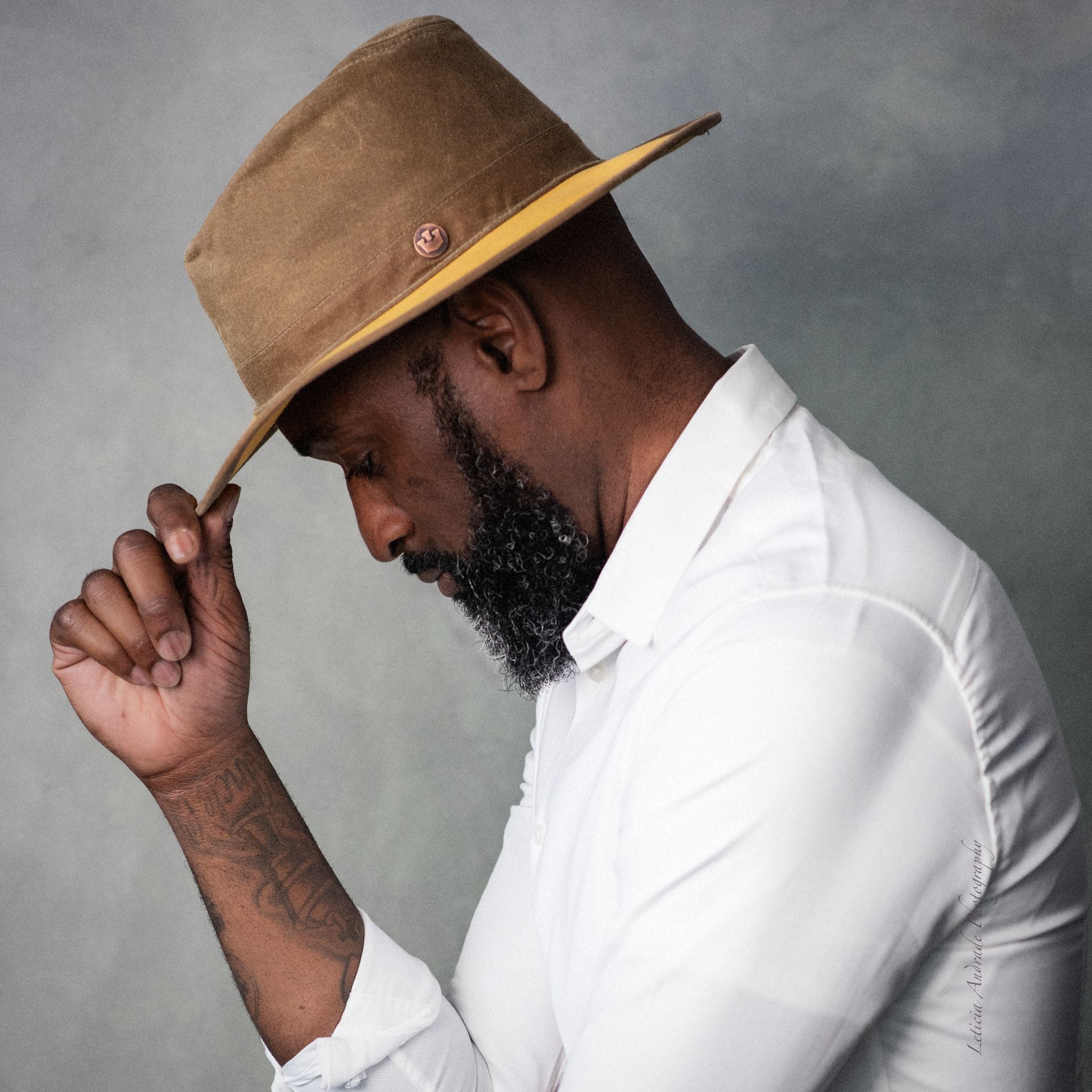 A man with a beard wearing a hat and a white shirt