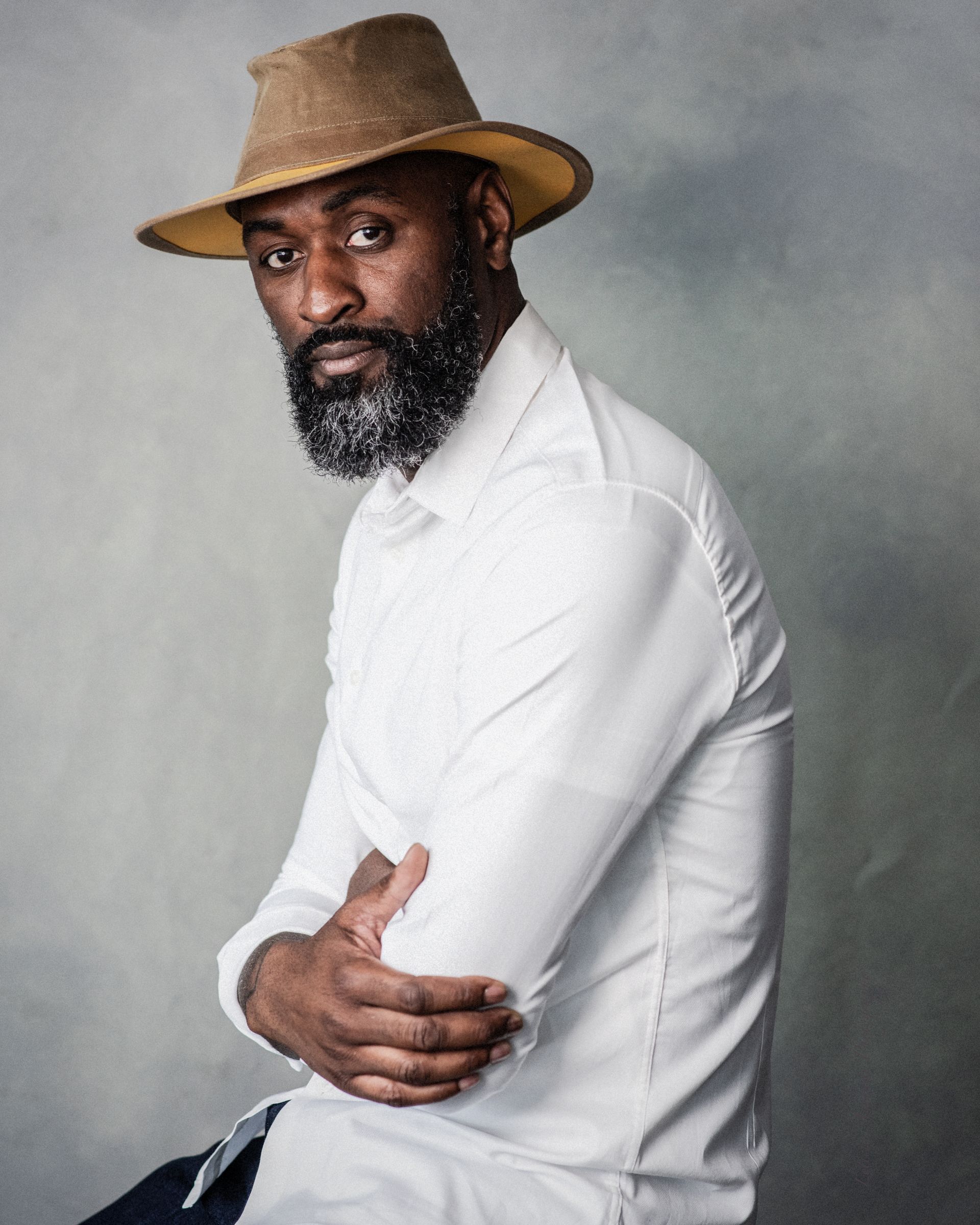 A man with a beard wearing a hat and a white shirt