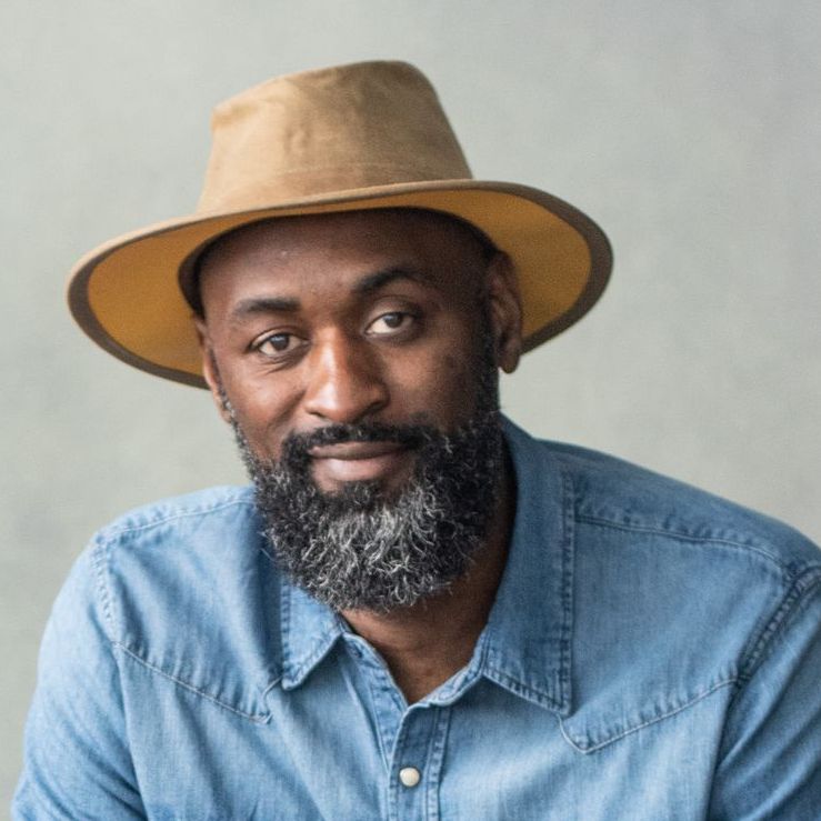 A man with a beard wearing a hat and a blue shirt