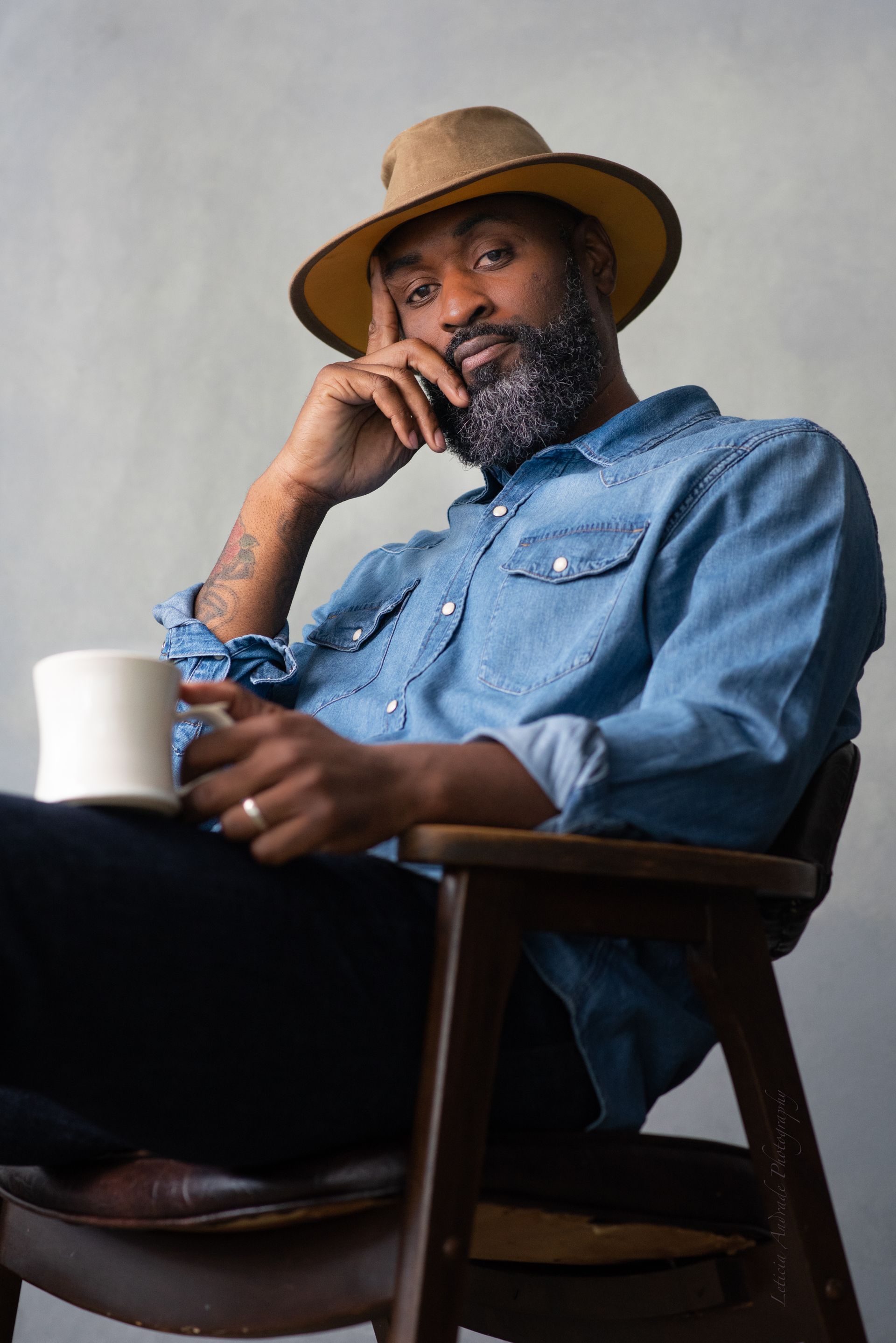 A man with a beard is sitting in a chair holding a cup of coffee.