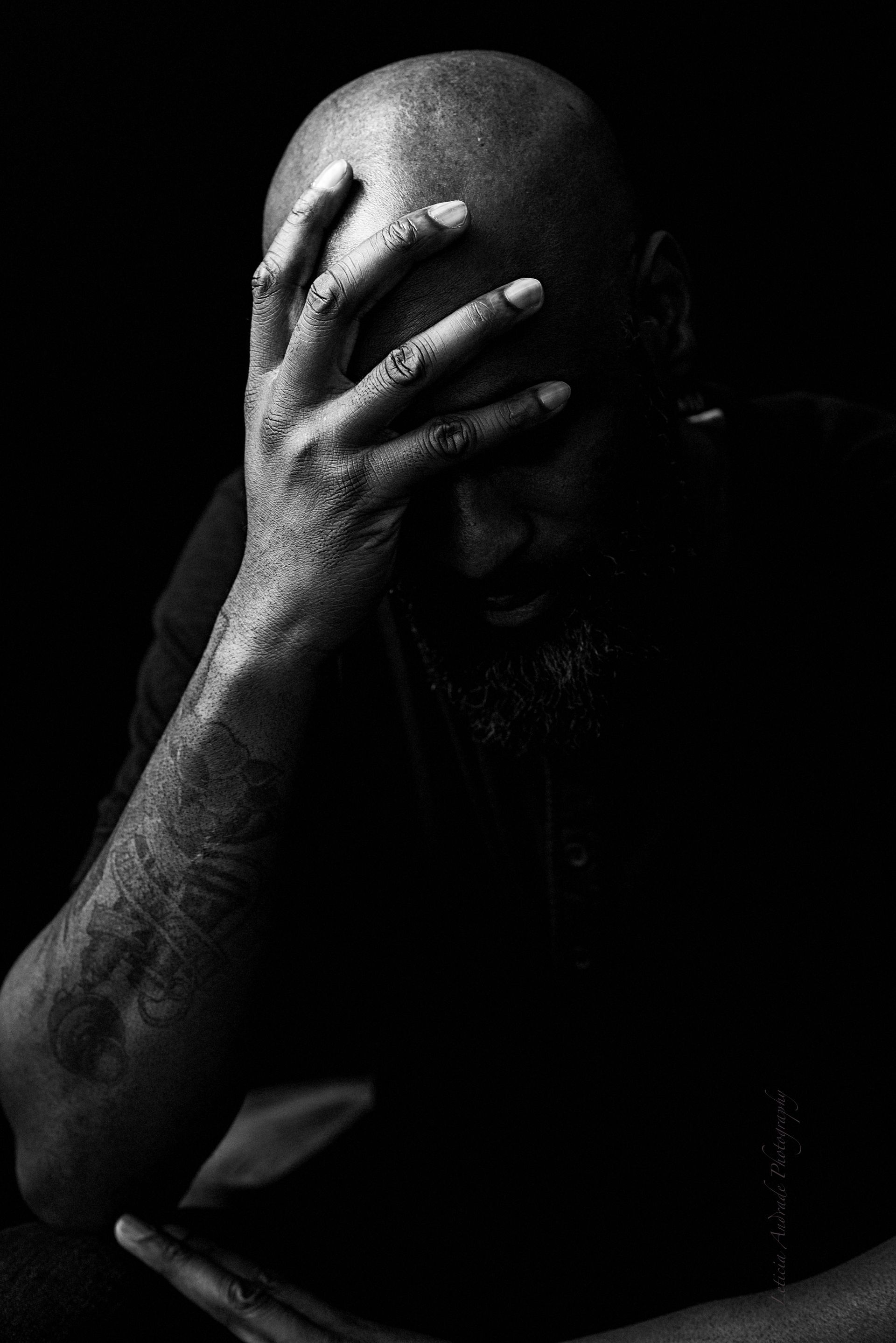 A man is covering his face with his hand in a black and white photo.