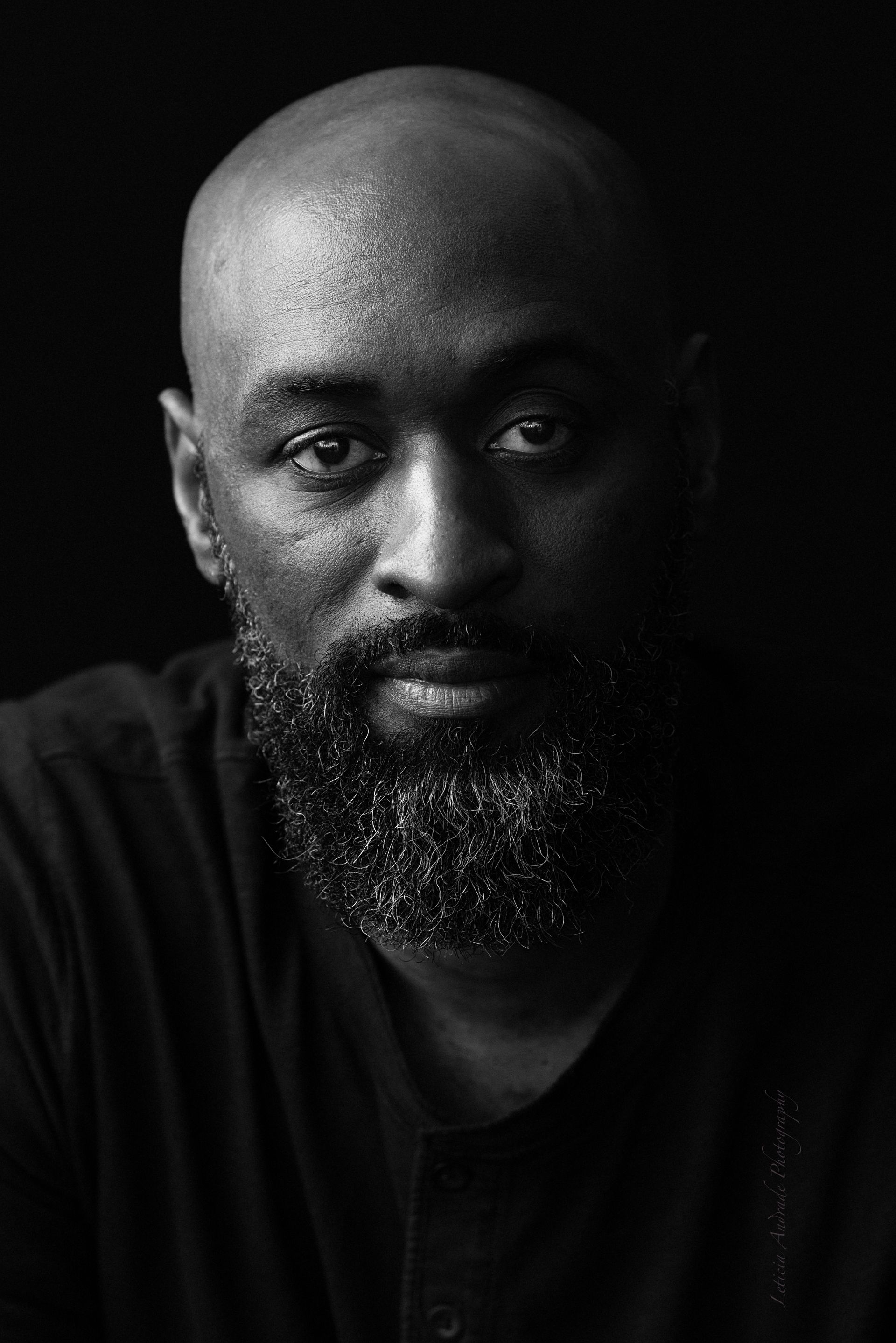 A black and white photo of a bald man with a beard.