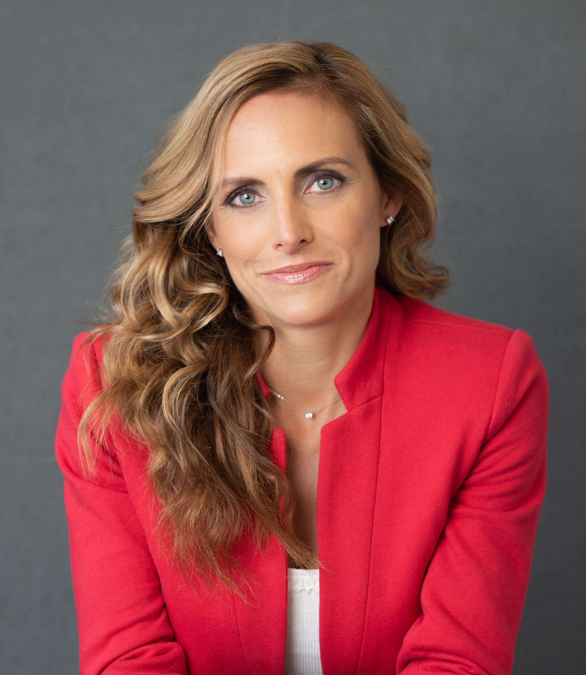 A woman is wearing a red jacket and smiling for the camera.
