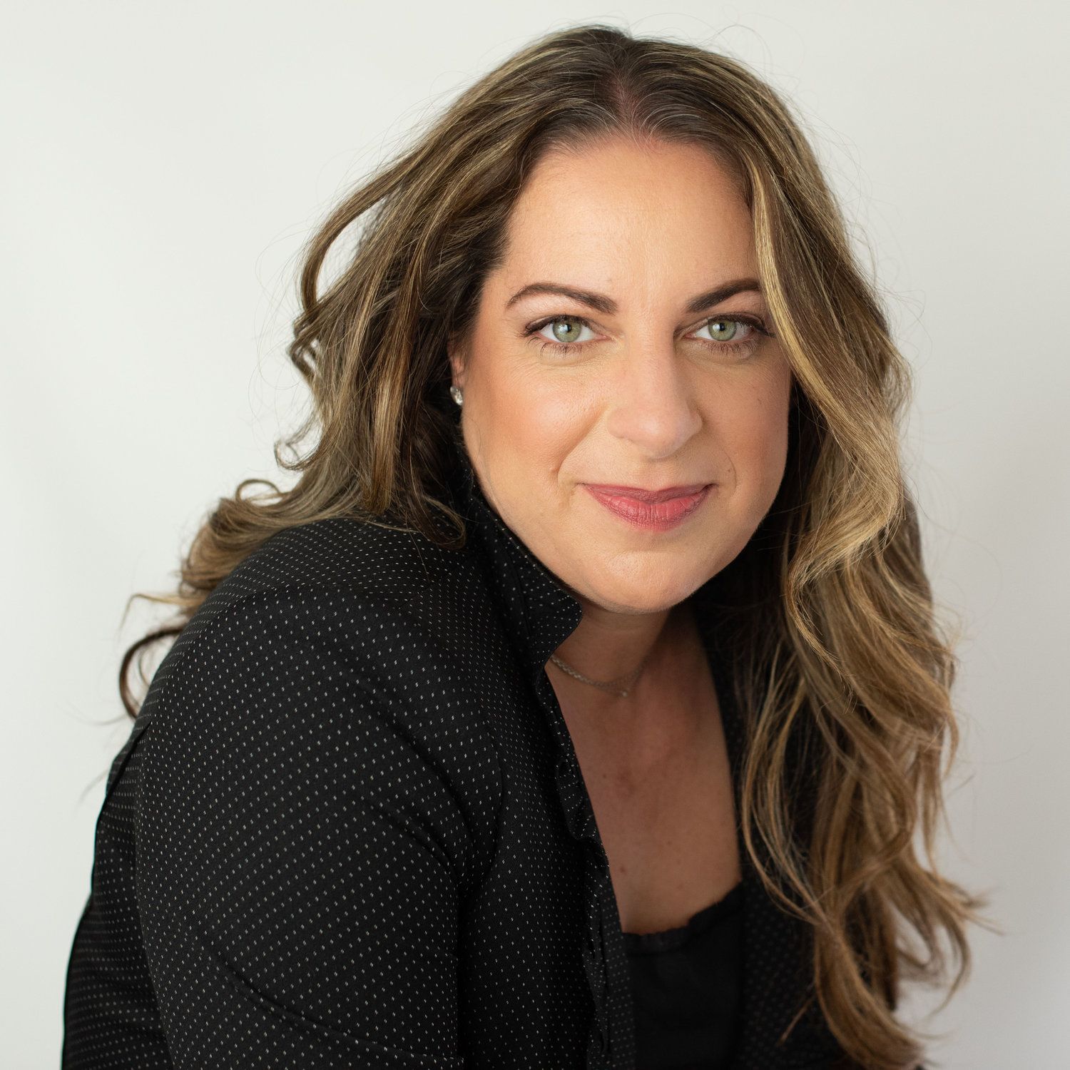 A woman with long hair is wearing a black sweater and smiling for the camera.