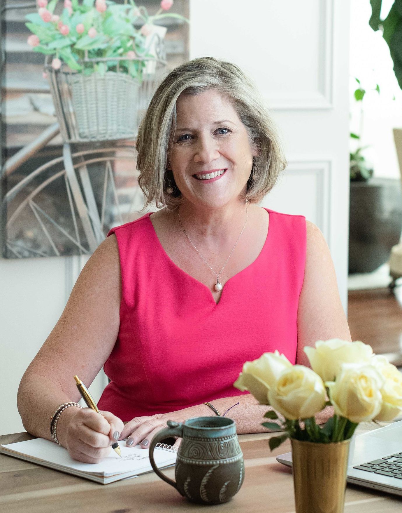 A woman is sitting at a table writing in a notebook.