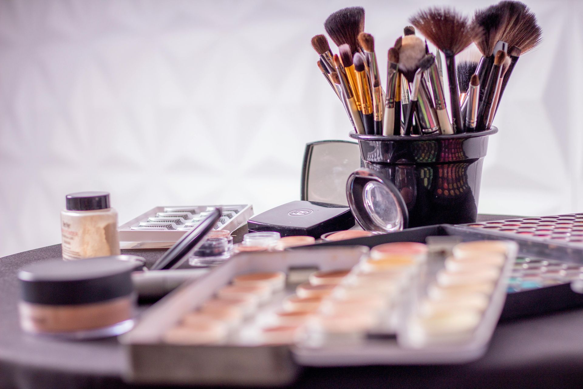A woman is applying makeup with a brush on a table.