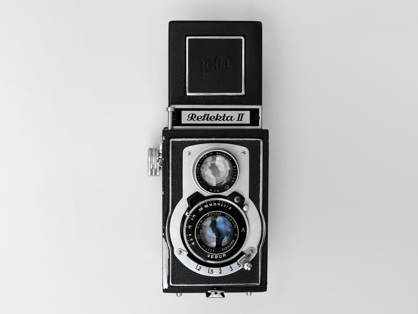 A black and white camera is sitting on a white surface.