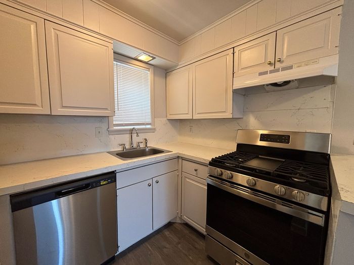 A kitchen with stainless steel appliances and white cabinets.