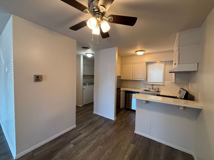 A kitchen with a ceiling fan and a stove top oven.